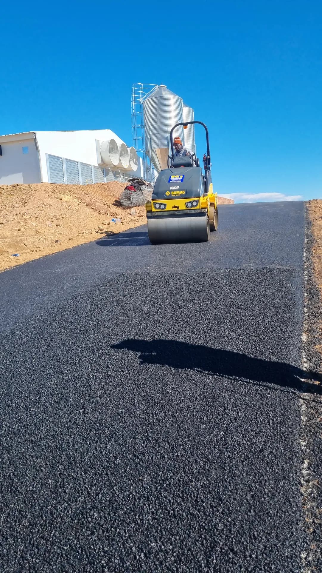 Roller finishing a freshly laid asphalt access road