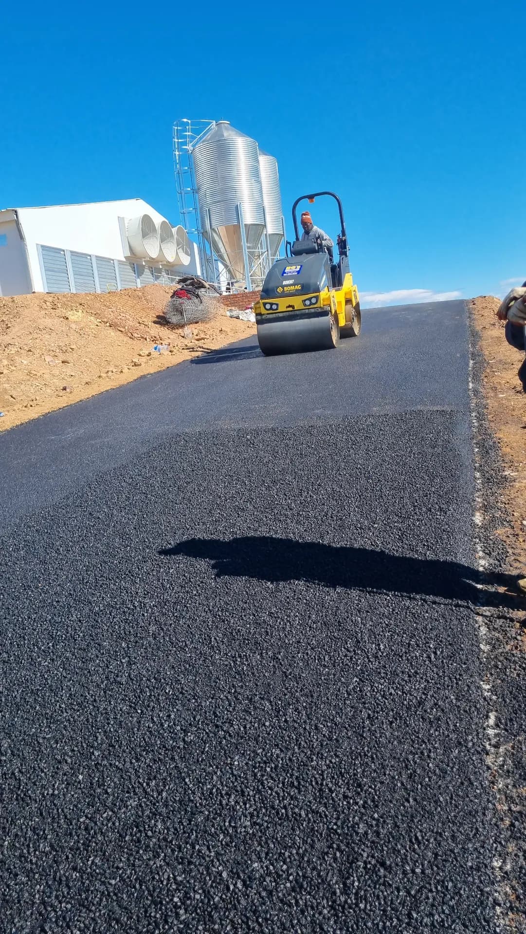 Smooth new asphalt surface with the roller working ahead