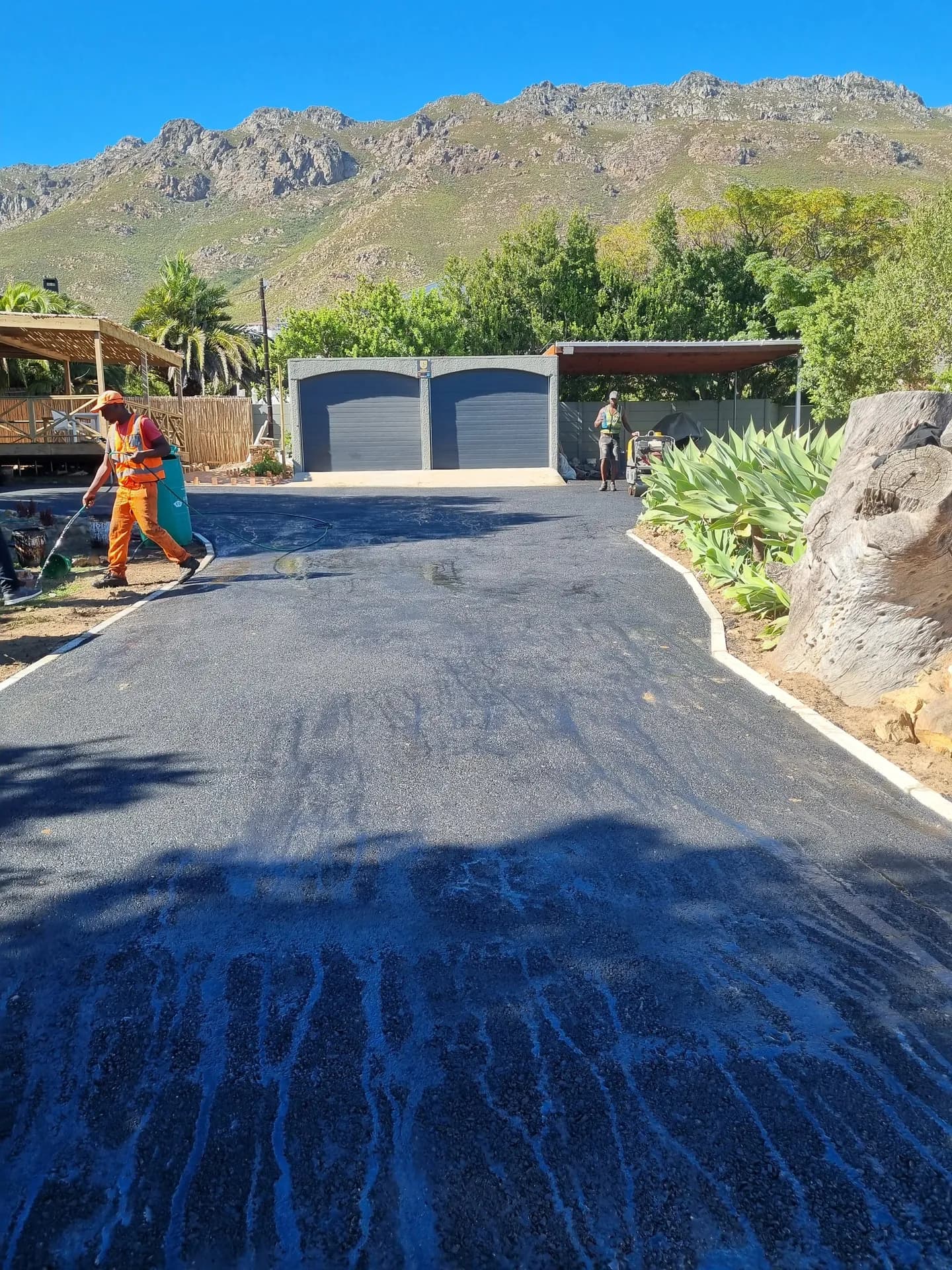 Crew finishing a curved asphalt driveway with kerbed edges